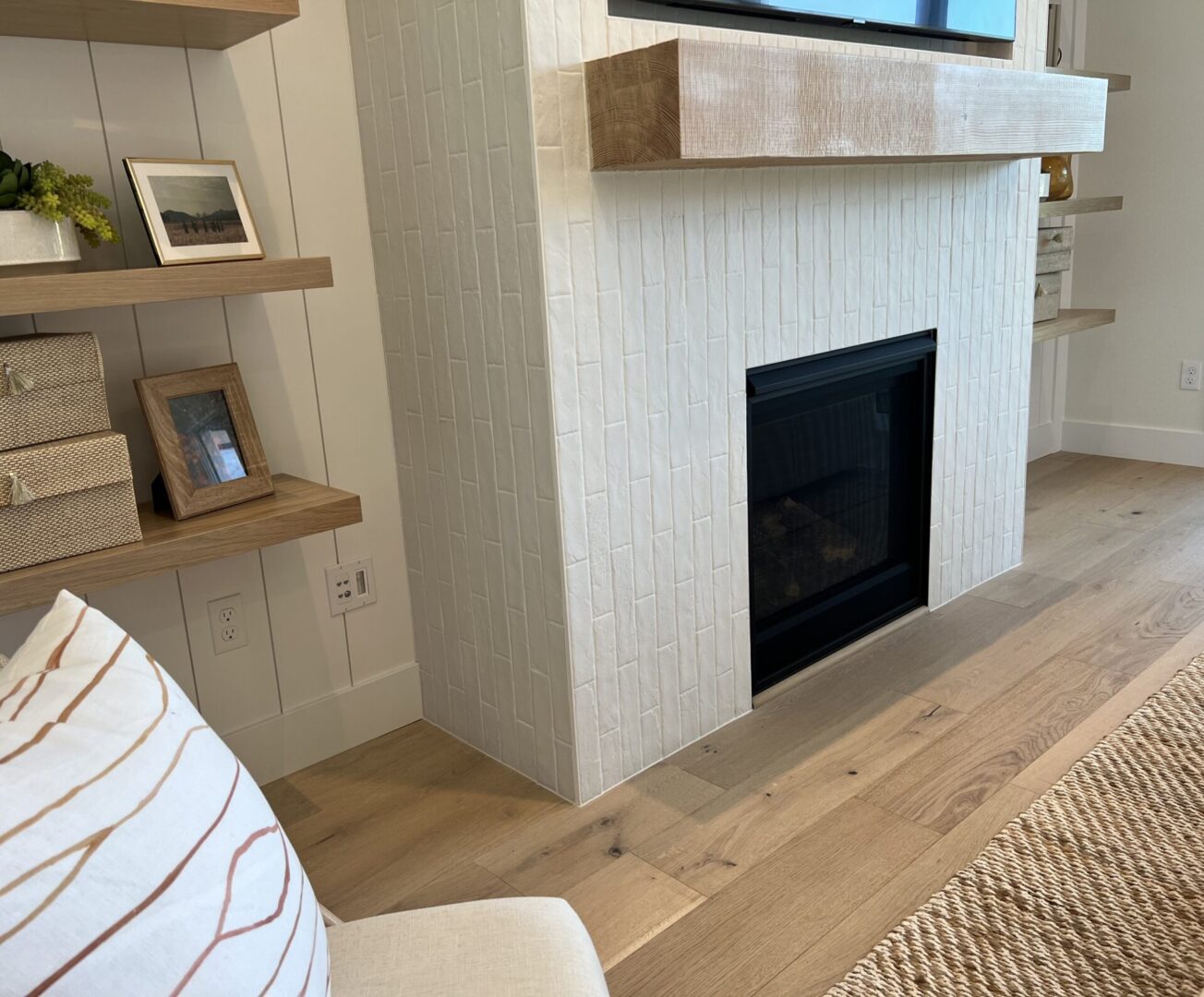 A fireplace with a tv above it and wooden shelves.