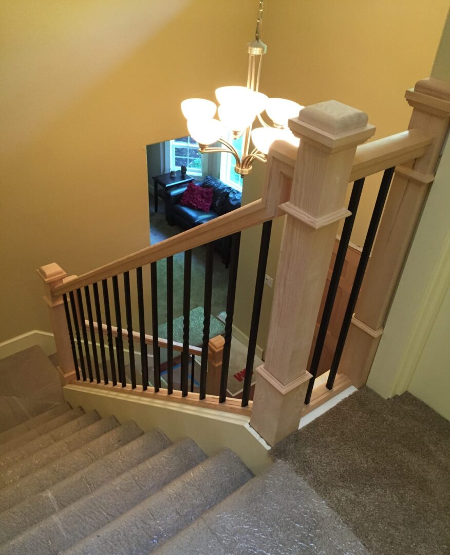 A staircase with black metal balusters and beige wood.