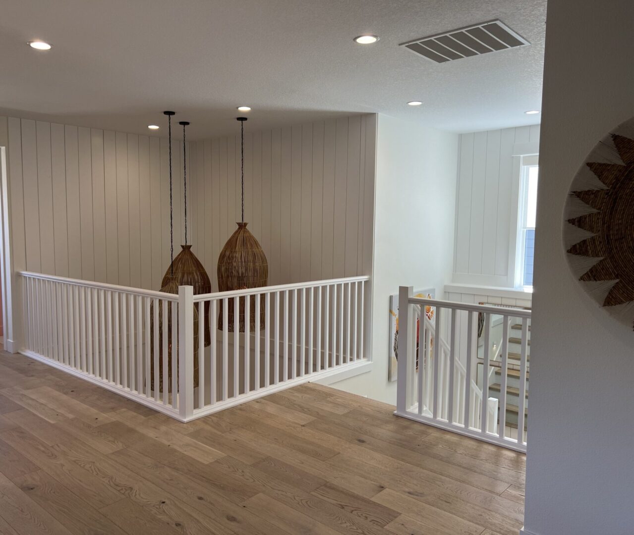 A room with two white railing and wooden floors.