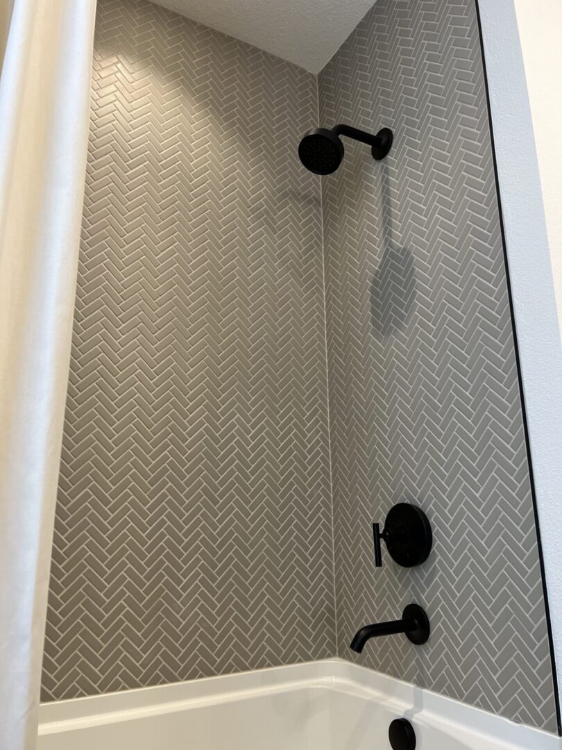 A shower with tiled walls and black fixtures.
