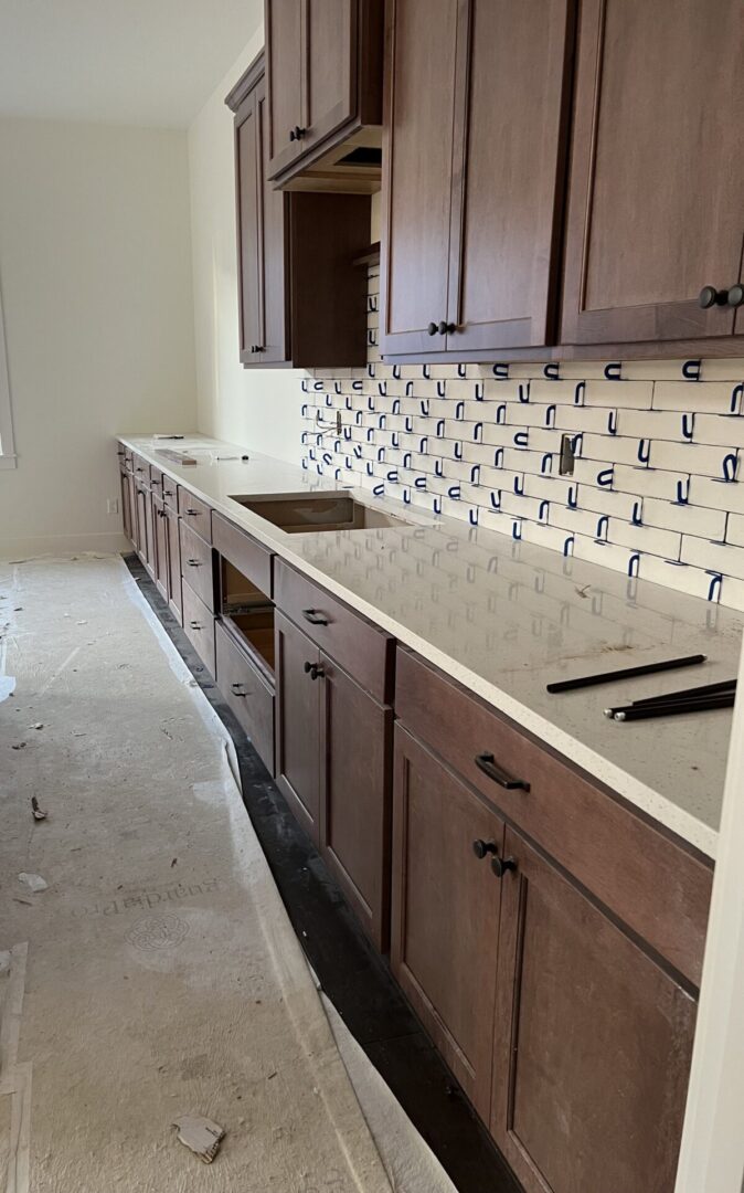 A kitchen with brown cabinets, subway tile, and white counters.
