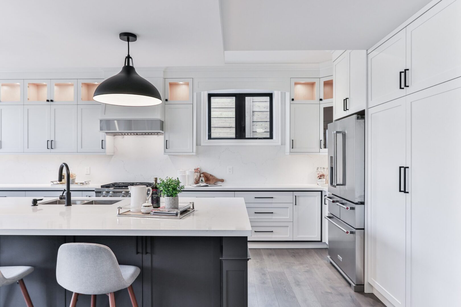 A kitchen with white cabinets and black island.