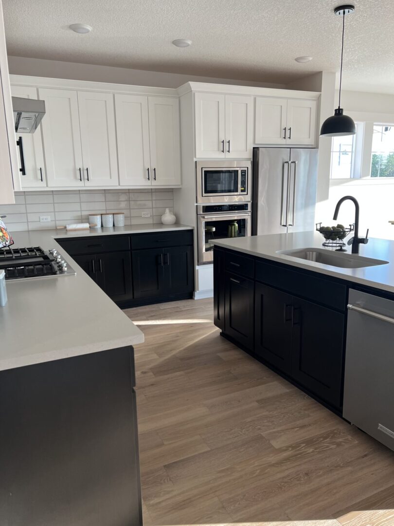 A kitchen with black and white cabinets, dishwasher, sink and microwave.